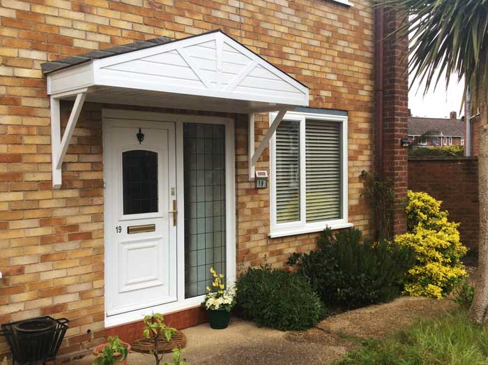 A wide door canopy installed over a door and side window on a house